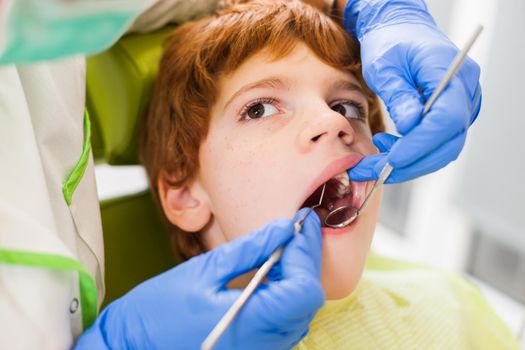 Dentist is examining teeth of a boy.