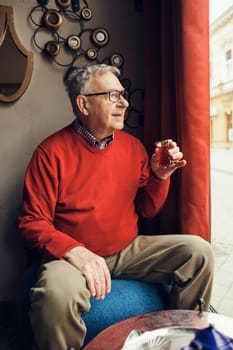 Senior man is drinking tea in a cafe.