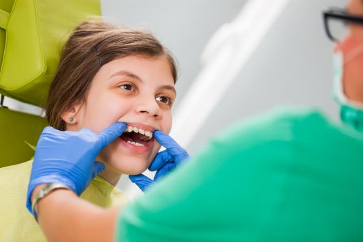 Dentist is examining teeth of a little girl.
