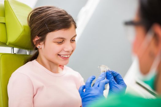 Dentist is teaching little girl about braces.