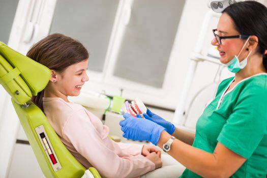 Dentist is teaching little girl about oral hygiene.