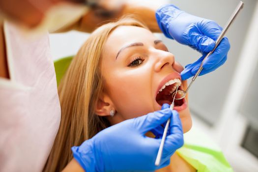 Young woman at dentist. Dentist is repairing her teeth.