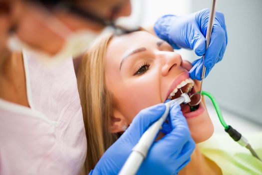 Young woman at dentist. Dentist is repairing her teeth.