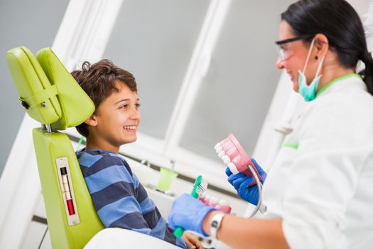 Dentist is teaching little boy about oral hygiene.