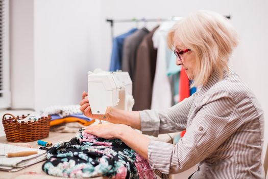 Adult woman is sewing in her studio.