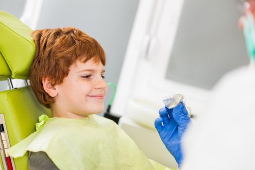 Dentist is teaching little boy about braces.