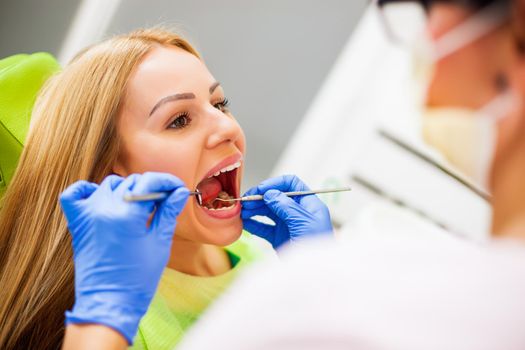 Young woman at dentist. Dentist is examining her teeth.