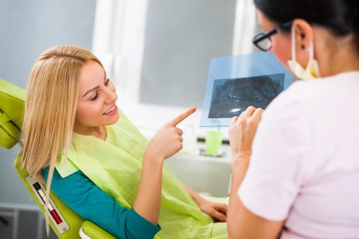Young woman at dentist. Examining x-ray image.