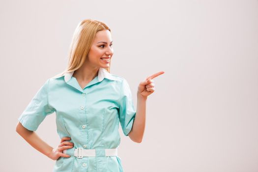 Portrait of young nurse who is pointing at advert.