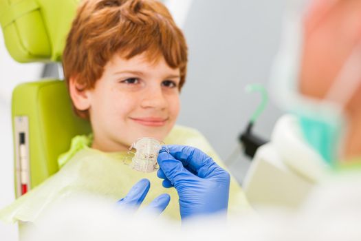 Dentist is teaching little boy about braces.