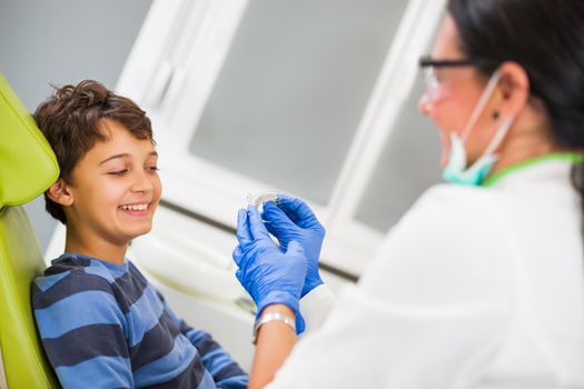 Dentist is teaching little boy about braces.