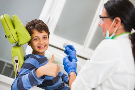 Dentist is teaching little boy about braces.