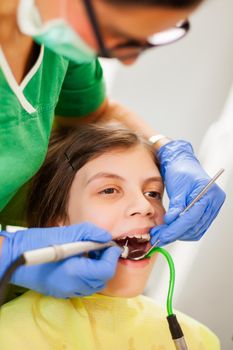 Dentist is repairing teeth of a little girl.