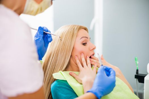 Young woman at dentist. She is afraid.