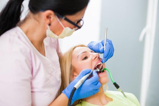 Young woman at dentist. Dentist is repairing her teeth.