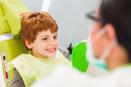 Little boy is looking at his teeth at dentist.