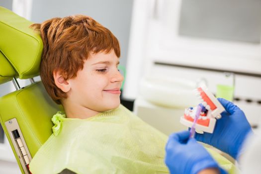 Dentist is teaching little boy about oral hygiene.