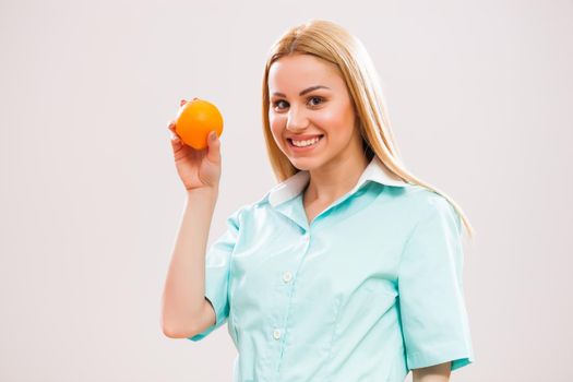 Portrait of young nurse who is holding orange fruit.