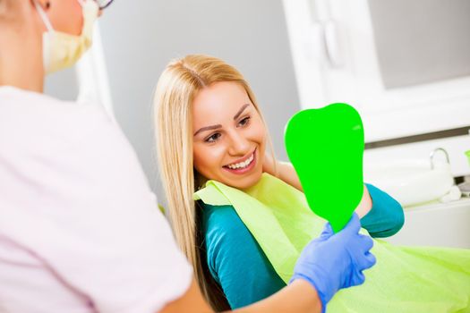 Young woman looking at her teeth after successful dental treatment.