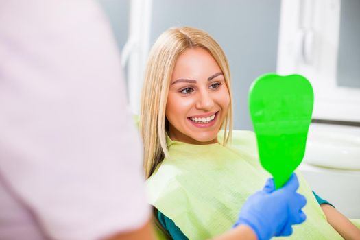 Young woman looking at her teeth after successful dental treatment.