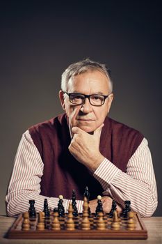 Portrait of senior man who is participating in chess game.