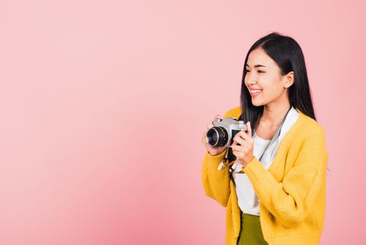 Attractive happy Asian portrait lifestyle beautiful young woman excited smiling photographer holding retro vintage photo camera ready to shoot isolated on pink background, tourism and vacation concept