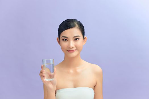 Beautiful woman with naked shoulders drinking a glass of water