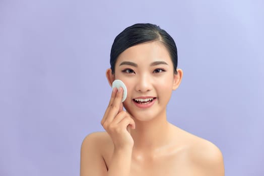 Portrait of young beautiful woman with healthy glow perfect smooth skin removing make up with cotton pad