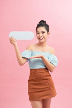 Portrait of young girl holding blank text bubble in specs isolated over pink background