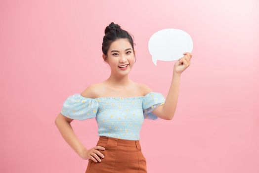 Young beautiful girl holding a white bubble for text, isolated on a pink background