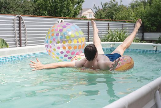 young man having fun at the swimming pool, splashing and laughing