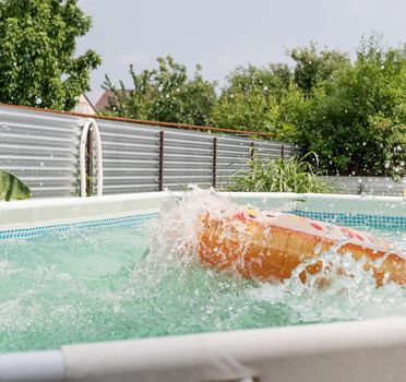 Inflatable swim circle in the form of donut in the swimming pool with splashes