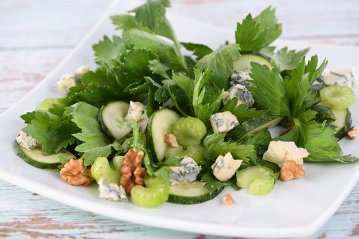Celery leaves and stalks salad with fresh cucumber slices, blue cheese, crushed nuts.