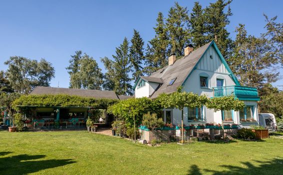 Beautiful country house situated in garden, with conifers, trees and flower. Summer beautiful garden concept.