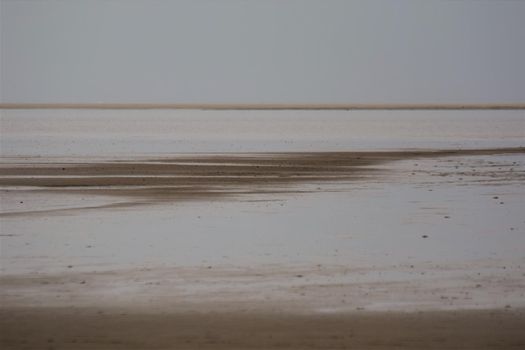 Beach of an island at low tide with a sandbank in the background