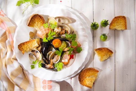 Presentation of a soup with seafood with roasted bread