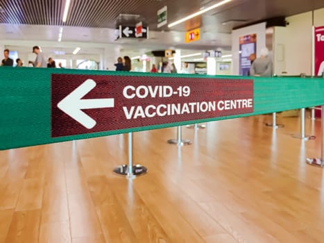 Green ribbon with a left arrow to indicate the Covid-19 vaccination centre. Covid-19 vaccination schedule. Coronavirus pandemic and prevention