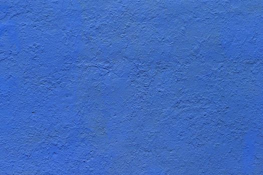 background and texture of flat thick painted matte blue surface under direct sunlight - new paint over fragments of old peeled one