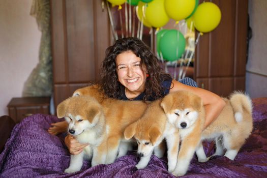 Handsome brunette girl have fun hugs and play with akita inu puppies.