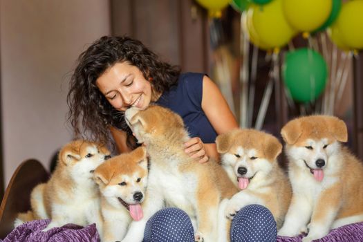 Handsome brunette girl have fun hugs and play with akita inu puppies.