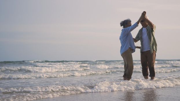 Happy Asian senior man and woman couple smile dancing resting relax on the beach honeymoon family sunny day, Romantic elderly enjoy travel summer vacation, plan life insurance at retirement couple