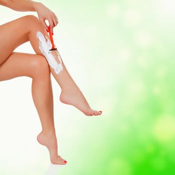 Woman shaving her legs, green abstract background