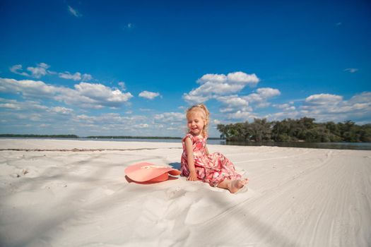 A little girl in a beautiful sarafna plays in the sand on the beach.