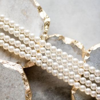 Pearl necklace on golden marble, ethical jewellery - luxury background, jewelry as a gift concept. Pearls are girl's best friends