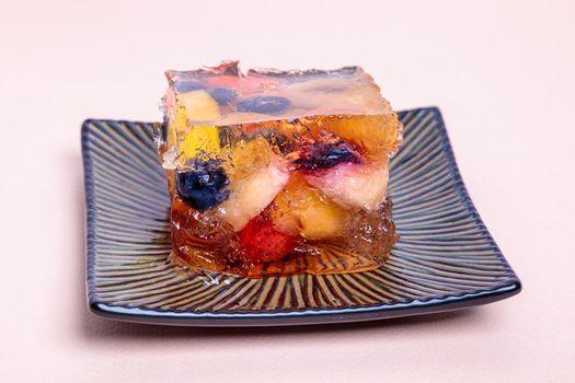 Jelly from different fruits and berries on a square saucer. Dessert. Close-up