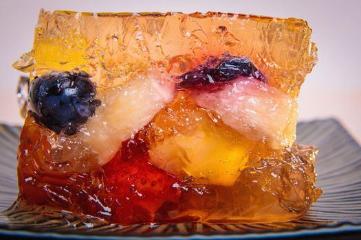 Jelly from different fruits and berries on a square saucer. Dessert. Close-up