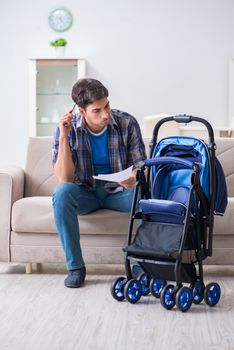Young father assembling baby pram at home