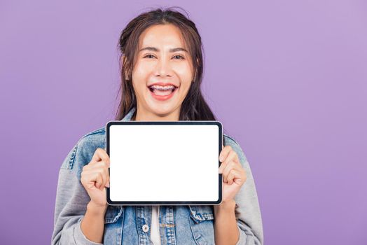 Portrait of Asian beautiful young woman confident smiling show blank screen with tablet computer, Happy lifestyle female teen showing digital tablet pc, studio shot isolated on purple background