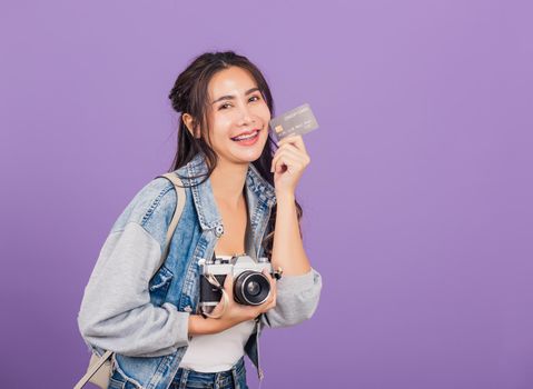 Happy Asian portrait beautiful young woman excited smiling photographer holding debit credit card bank and retro vintage photo camera ready travel isolated on purple background, tourism and vacation