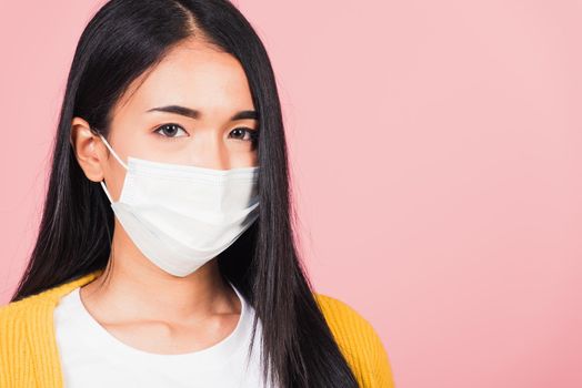 Closeup face Asian beautiful young woman wearing medical mask protection against germs for prevent infection coronavirus, COVID-19, studio shot isolated on pink background, medical health care concept